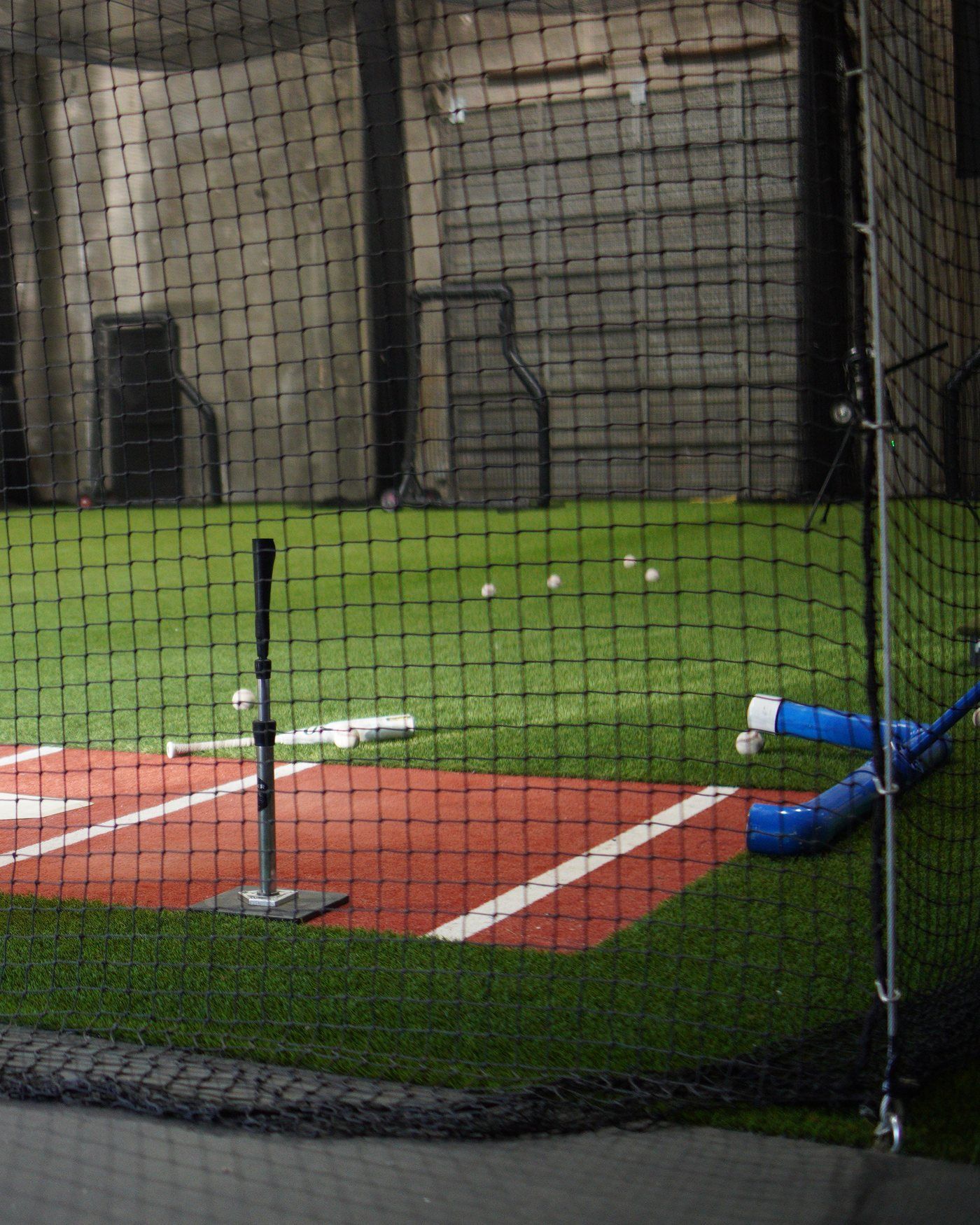 A batting tee on home plate inside a cage at The Bears Den in Sacramento