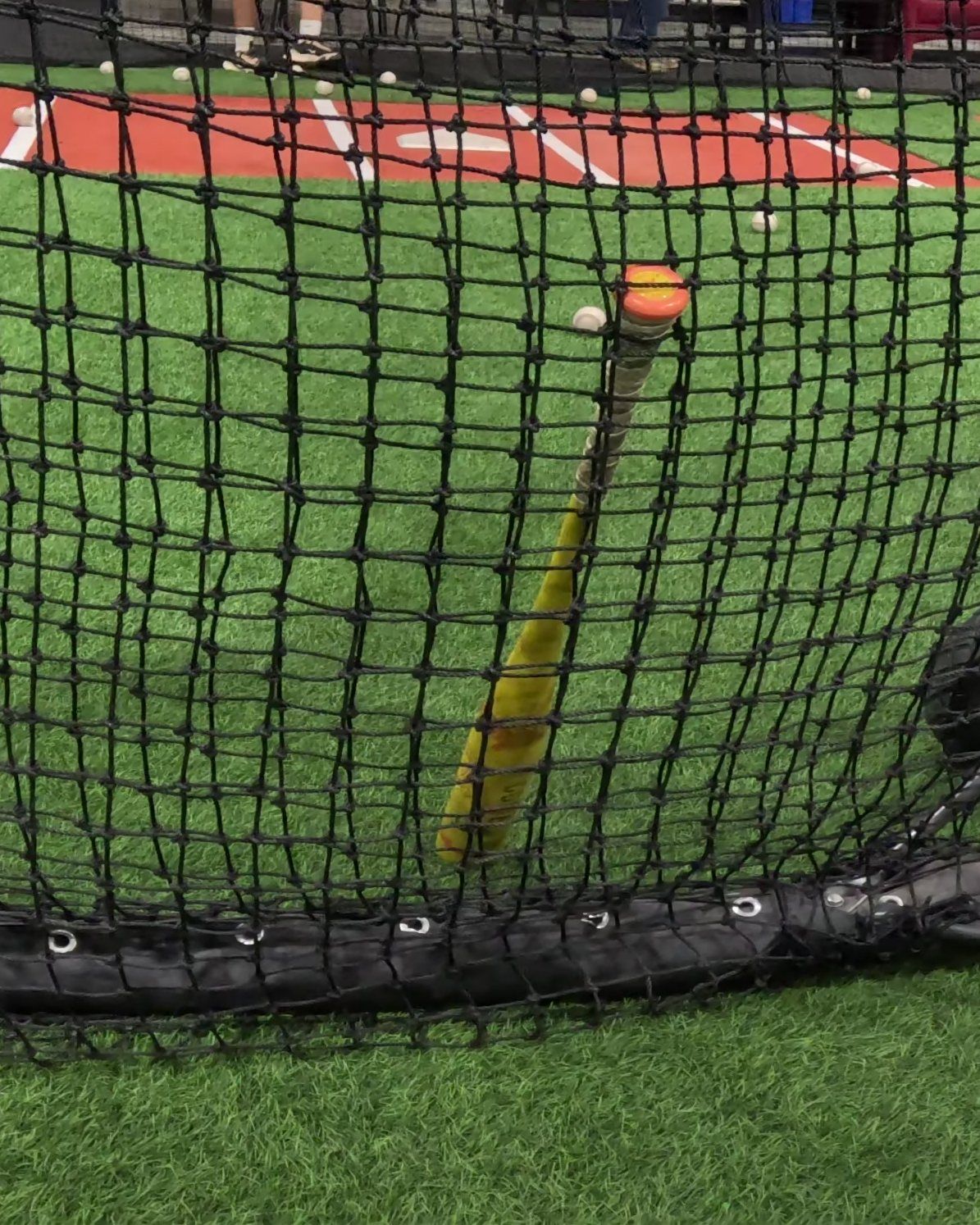 A pitching L-screen on wheels with a bat on the turf at The Bears Den in Sacramento